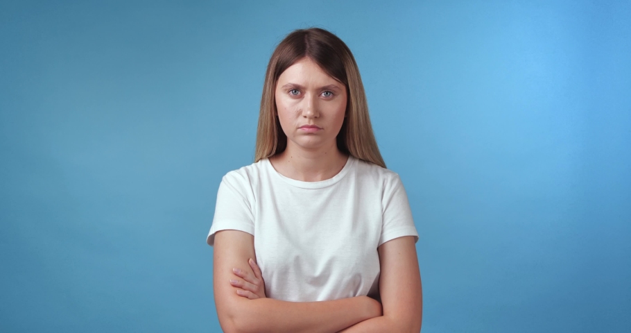 Displeased young woman crossing arms on light blue background | Shutterstock HD Video #1097599697