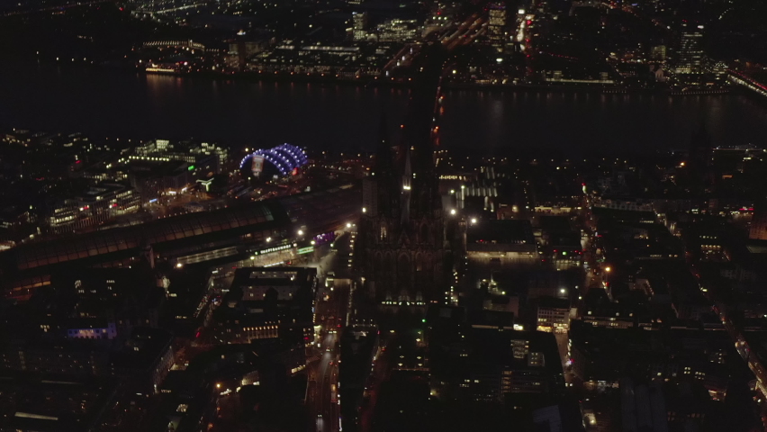 Aerial shot of gothic Cologne Cathedral and surrounding development in urban borough near Rhine river at night. Cologne, Germany