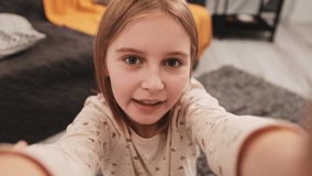 Preteen girl influencer making live stream with camera smartphone from home. Pretty kid child recording video content for social media blog