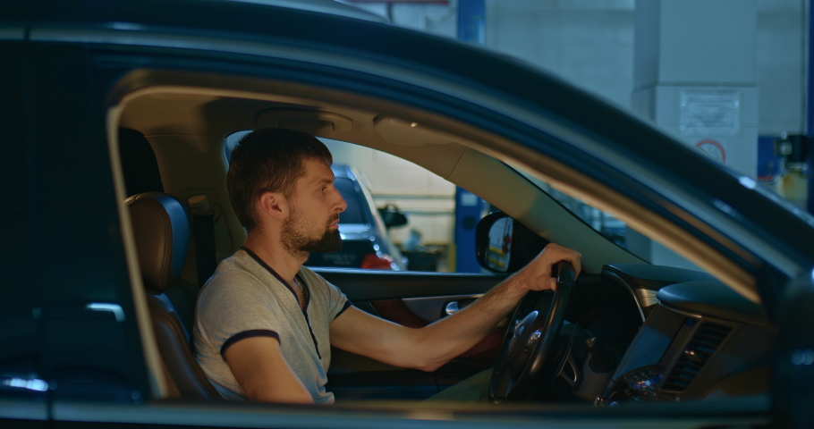 Car pulls into a car service or garage. Driver is driving through a service station or garage. Portrait of the driver in the passenger compartment on the side. Royalty-Free Stock Footage #1097606891