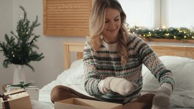 Caucasian woman opening and trying on Christmas presents in her bedroom. Shot with RED helium camera in 8K.    