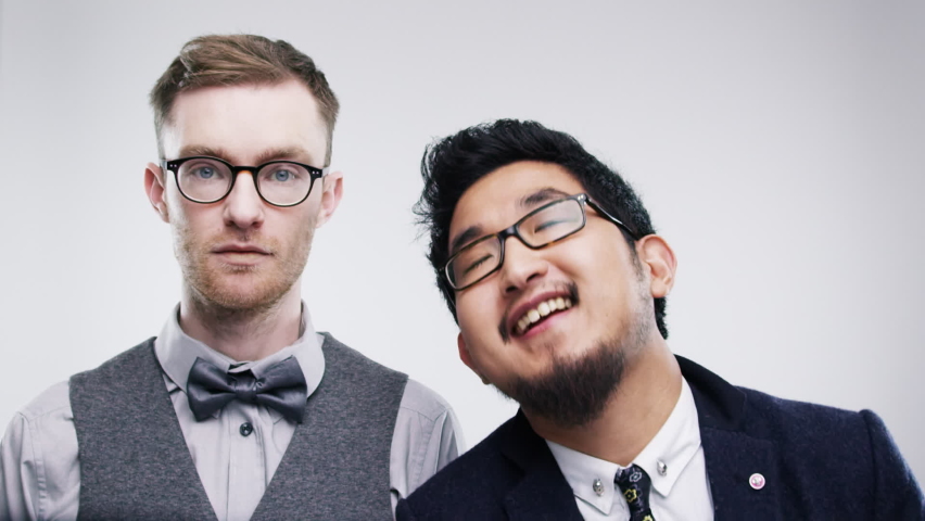 Party, portrait and man dancing with friend feeling annoyed on a white studio background. Photobooth, wedding and diverse men having fun at social event to celebrate with joy on a studio backdrop