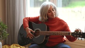 elderly woman tuning guitar at home - Powered by Shutterstock - Get 15% off with code: PIKWIZARD15