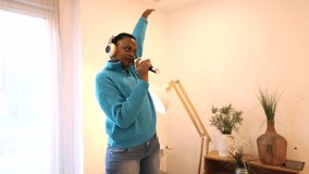 pretty african american woman singing and listening to music on the sofa at home