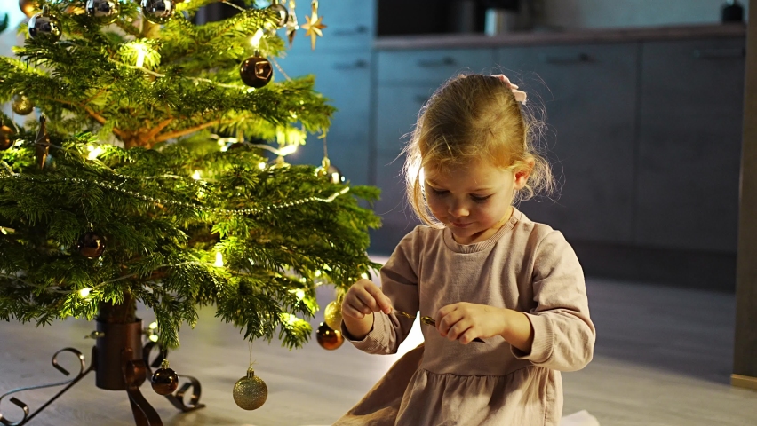 A cute little girl hanging balls on the Christmas tree at home. High quality 4k footage | Shutterstock HD Video #1097615725