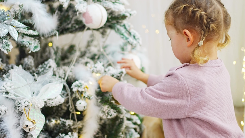 Very nice charming little girl blonde in pajamas near Christmas trees in bright interior of the house. High quality 4k footage | Shutterstock HD Video #1097615729