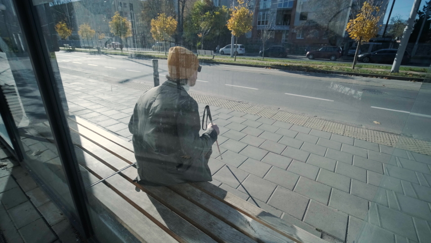 Blind man waiting for bus at a bus station