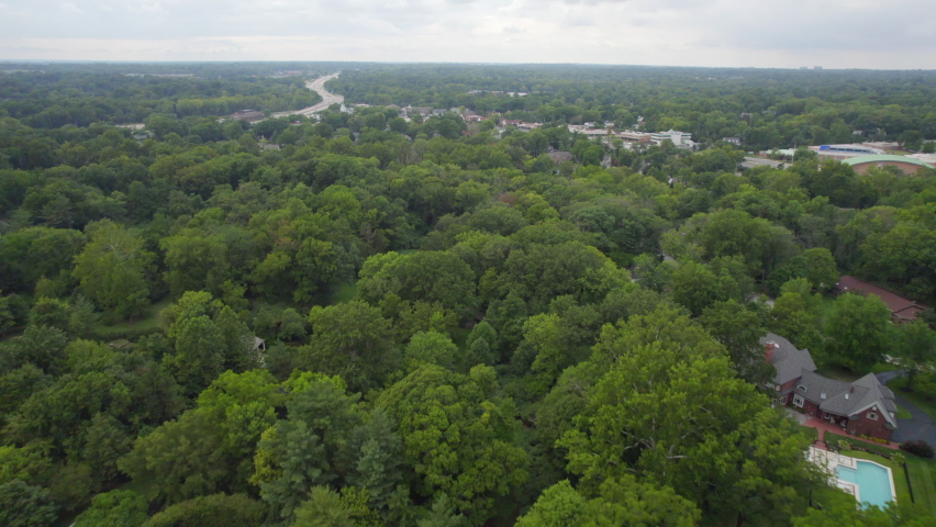 Flyover nice neighborhood in beautiful Ladue of St. Louis, Missouri and towards retail shops on Clayton Rd and highway 40 on a cloudy summer day.