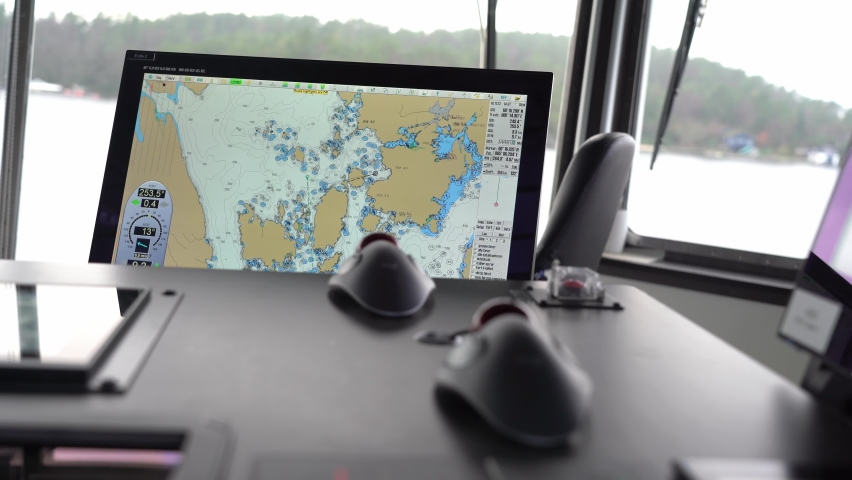 Ship captain uses computerized chart while navigating ship. Over shoulder shot with ECDIS screen in focus with blurred foreground Royalty-Free Stock Footage #1097627251