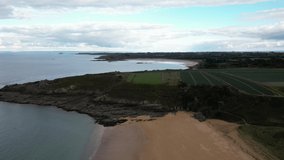 Drone flying over Touesse beach at Rozven and surrounding landscape, Saint-Coulomb in Brittany, France. Aerial forward