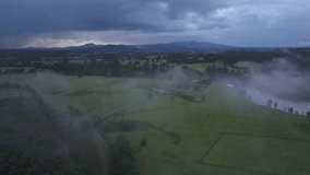 Low stormy clouds over green fields, Nambucca Valley in New South Wales, Australia. Aerial forward