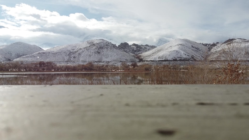 Low angle view of calm Diaz lake surrounded by snow covered mountains during fresh snowfall. California, USA.