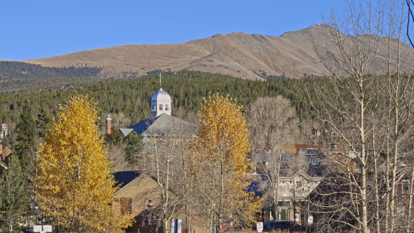 Handheld domed building with Bald mountain in the distance and golden Aspens. Filmed in the town of Breckenridge Colorado, during the winter.