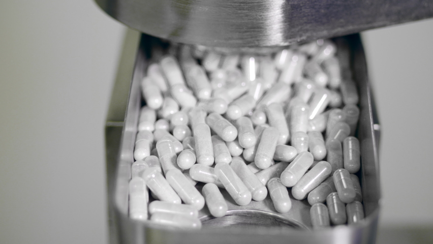 Capsule pills are falling from the metal conveyor