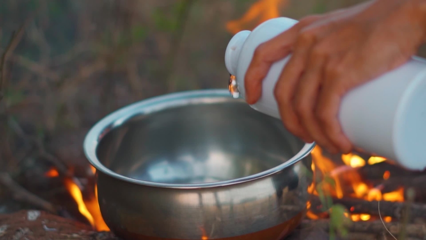 Close up slow motion shot of hands of girl pouring water in vessel. Cooking food outdoor. Vacation picnic concept. | Shutterstock HD Video #1097630787