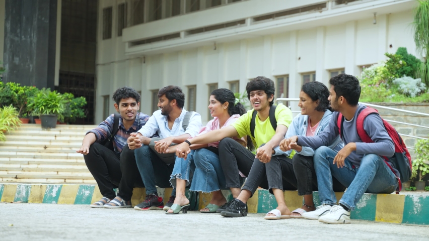 Happy smiling group of students raising hands while sitting at college campus - concept of celebrating, freedom and togetherness Royalty-Free Stock Footage #1097631421