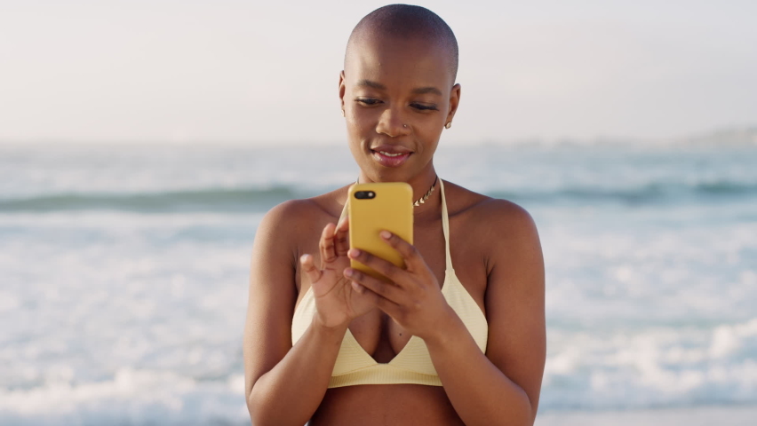 Black woman, phone texting and beach with smile for social media, communication or web app. Happy african woman, bikini or smartphone for social network, online dating or chatting on internet by sea | Shutterstock HD Video #1097632279