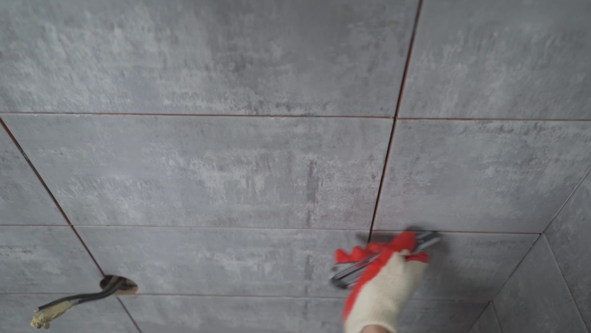 Male worker tiling a wall. A worker cleans the seams on a ceramic tile with a knife. | Shutterstock HD Video #1097633741