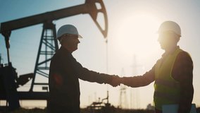 handshake business oil contract. handshake a worker and businessman shaking hands against the backdrop of an oil pump. sun oil extraction business concept. silhouette handshake business contract - Powered by Shutterstock - Get 15% off with code: PIKWIZARD15