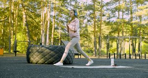 4k footage of a young woman during a workout on an outdoor sports ground - she squats on one leg, training her leg muscles. The concept of keeping fit. 60fps video.