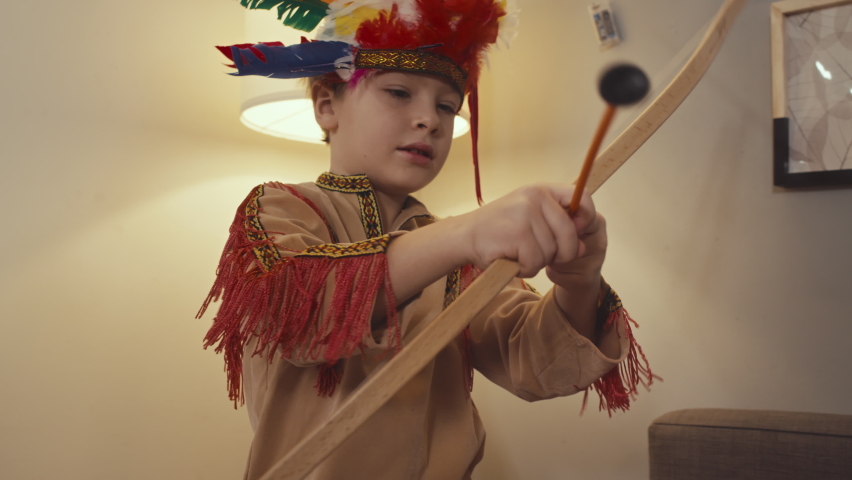 Medium of cute blond boy playing with toy bow in playroom