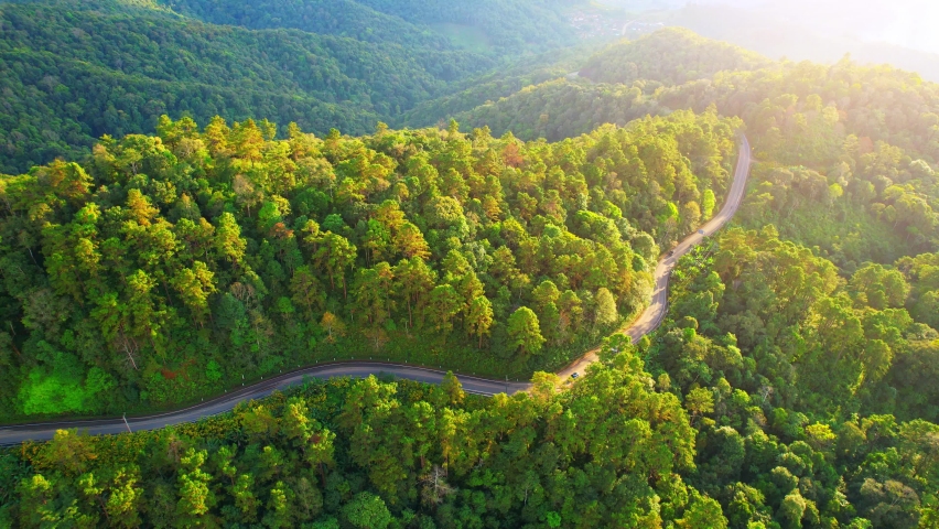Drone is flying over a winding road in a green tropical forest, high mountain scenery during sunset. nature, transportation and tourism concept. Mae Hong Son, Thailand. aerial view footage. 4k
