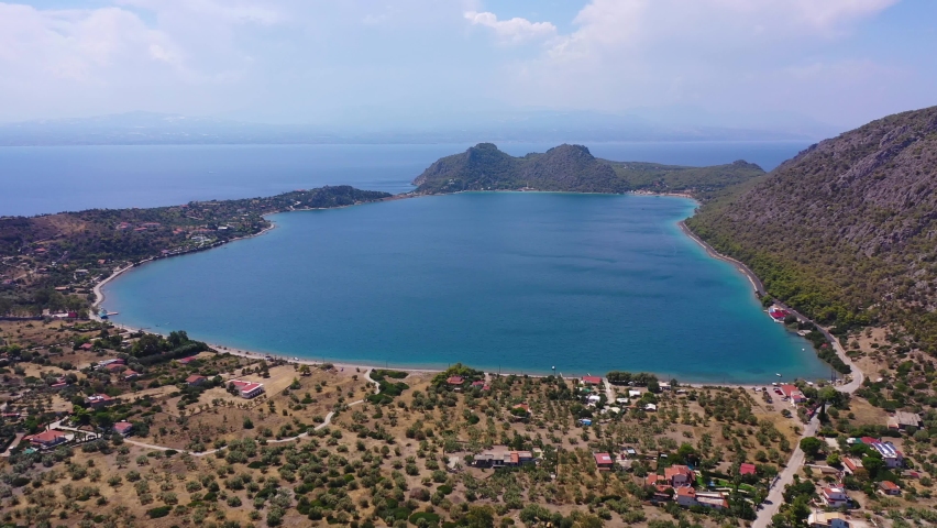 Aerial drone video of scenic lake Vouliagmeni in Corinthia near famous lighthouse of Heraion and city of Loutraki featuring crystal clear turquoise beach and calm waters, Perachora, Greece