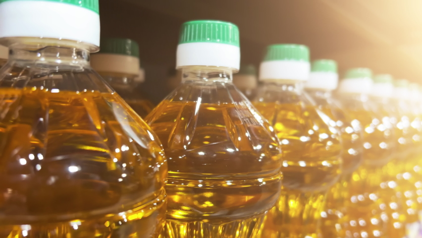 Sunflower or corn oil in plastic bottles lined up on the shelf in a supermarket or a warehouse. Close Up shot Royalty-Free Stock Footage #1097650691