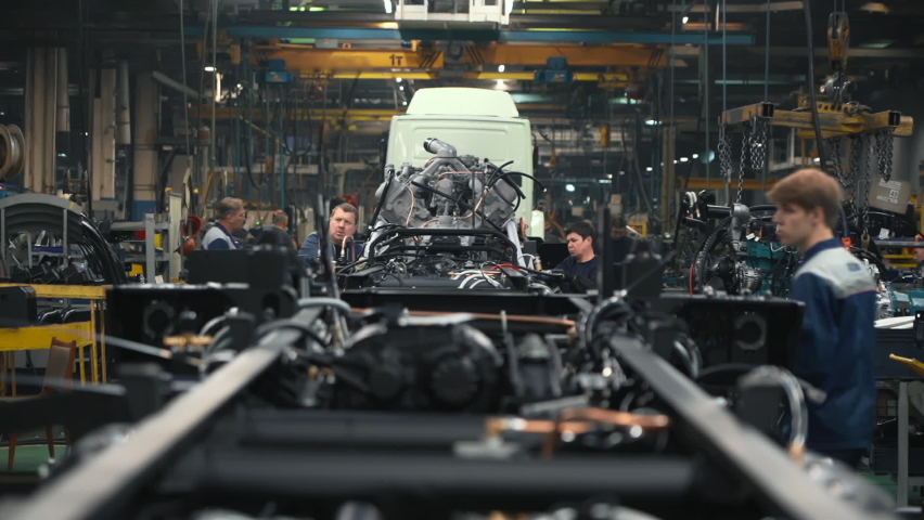Automotive Equipment Production Facility. A Production Line is filled with multiple Vehicles Parts at the Automotive Factory. Workers are Supervising the Manufacturing Process at Automotive Plant.