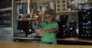 African American female waitress with afro hair serving a beer in a pub