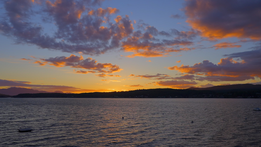 Establishing shot of ocean sunset over mountains in slow motion at summer day in Vancouver, Canada, North America. Evening time on September 2022. Still camera. ProRes 422 HQ.