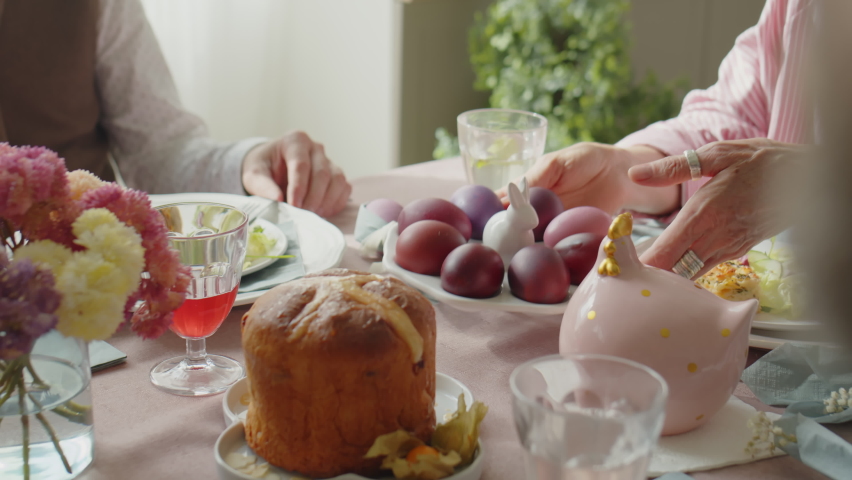 Family passing plate of dyed eggs to father and little daughter while having festive dinner on Easter day Royalty-Free Stock Footage #1097664137