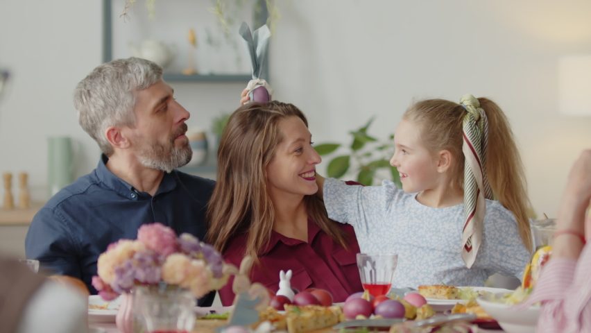 Cheerful little girl and parents playing with Easter egg on holiday dinner with family Royalty-Free Stock Footage #1097664859