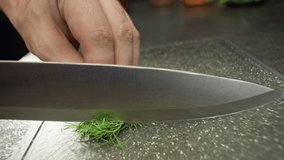 Slow motion close-up video of slicing dill on a cutting board. High quality 4k footage