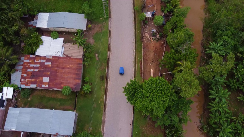 Tracking Shot Of Toktok Crossing Rural Road In Poor Residential Area, Huicungo, Peru