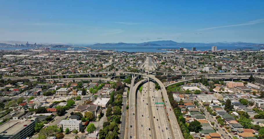 Oakland California Aerial v8 forward flying above macarthur freeway capturing winding interchange, cityscape across neighborhoods with san francisco bay view - Shot with Mavic 3 Cine - April 2022 Royalty-Free Stock Footage #1097668267