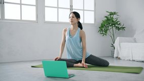 Young Asian woman doing yoga with laptop PC in the room. Remote training. Body care.