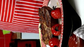 Chef decorates fried meat in plate with fried cherry tomatoes and rosemary. Vertical video.