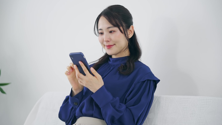 Young Asian woman using a smart phone in the room. Royalty-Free Stock Footage #1097679999