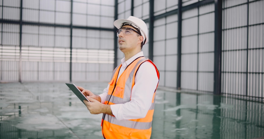 warehouse manager with tablet and radio communication his worker working in background in warehouse distribution center environment. Business warehouse inventory,contruction warehouse