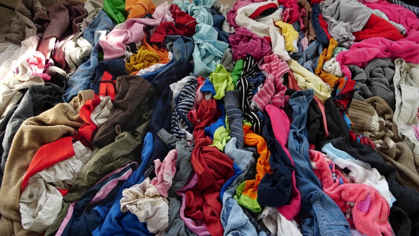 Used clothes. A big pile of old unnecessary clothes. Fast fashion, garbage and pollution Royalty-Free Stock Footage #1097688087