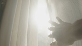 Hand slowly reaches out to open and reveal window curtain as sun shines through. Flare and sunlight from outside. Moving blinds to see the light. Symbol of hope positivity new energy and ideas vision - Powered by Shutterstock - Get 15% off with code: PIKWIZARD15