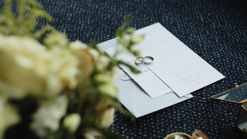 Wedding rings and invitations, wedding decoration, close-up bride attributes, wedding accessories, slow motion shot.