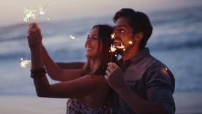 Couple, sparkler and having fun on the beach at sunset while celebrating new years eve with friends. Boyfriend and girlfriend with sparkle to celebrate on a seaside vacation or holiday in Bali - Powered by Shutterstock - Get 15% off with code: PIKWIZARD15
