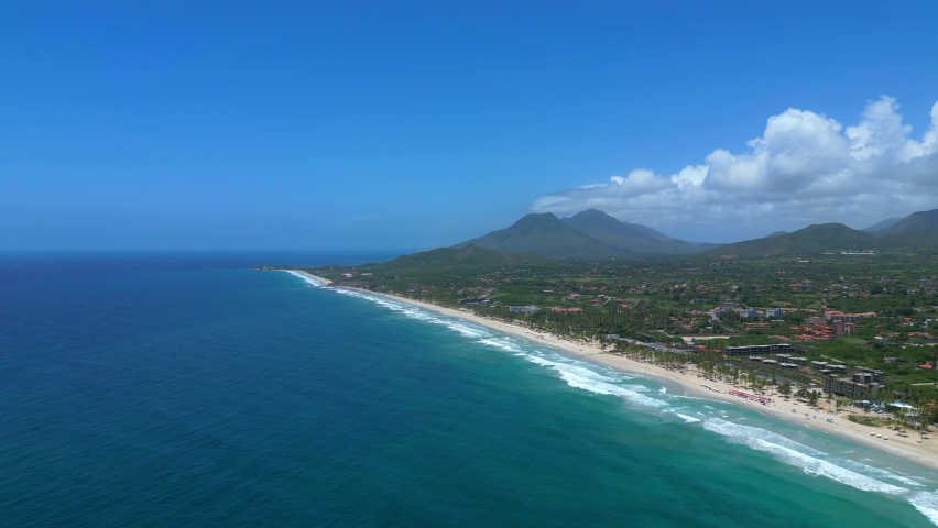 Aerial static shot of the El Agua tropical beach on the Margarita island. Turquoise water of the Caribbean big waves and clear blue sky. Vacation in beautiful Venezuela Royalty-Free Stock Footage #1097693759