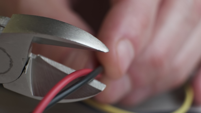 Pliers tool cutting red electric wire closeup on black background, service and repairing concept. cuts electrical wires with pliers, installation of household electrical appliances. Royalty-Free Stock Footage #1097695389