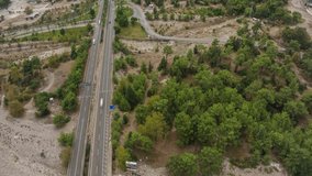  Highway along the city at the foot of the green mountain. Top view. Timelapse. Aerial drone video footage. Landscape
