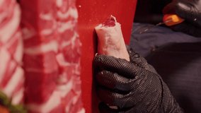 Vertical Screen: Butcher in gloves aggressively slicing raw lamb loin chops. Man hands cutting raw lamb meat for grill.