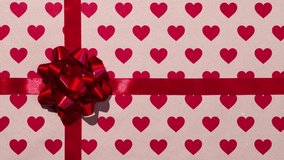 Unwrapping gift revealing a green screen - Stop Motion Animation - Red bow on a craft paper background with hearts. Chroma key