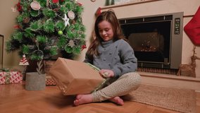 Cute girl opening christmas present. High quality 4k footage